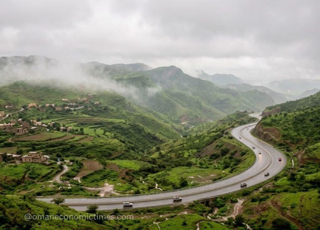 24 - Oman Economic Times Winding highway through a green, misty valley with small village buildings on the left.